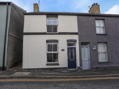 A street view of a two storey terraced house with a dark blue door and cream brick facade at Amelie Cottage Beaumaris Anglesey
