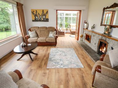 A living room with sofas a wooden coffee table a rug a fireplace and a painting of donkeys at Glebe Farm Cottage in Rathfriland County Down