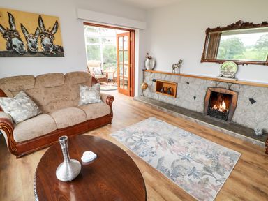 A living room with a couch coffee table fireplace and open doors to a sunroom at Glebe Farm Cottage in Rathfriland County Down