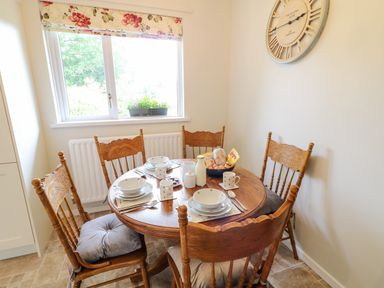 A dining area with a round wooden table set for four and wooden chairs at Glebe Farm Cottage in Rathfriland County Down
