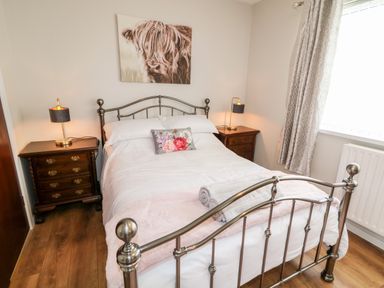 A bedroom with a metal bed frame bedside tables with lamps and a window with curtains at Glebe Farm Cottage in Rathfriland County Down