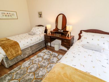 A bedroom with two single beds a wooden dressing table and two lamps at Glebe Farm Cottage in Rathfriland County Down