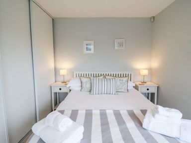 A bedroom with a bed with pillows and folded towels on a striped blanket at 9 Cedars in St Agnes