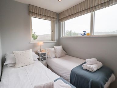 A bedroom with two single beds bedside table and window blinds at 9 Cedars in St Agnes
