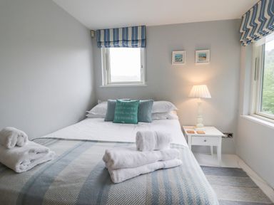 A bedroom with a bed white linens pillows towels bedside table and lamp at 9 Cedars in St Agnes