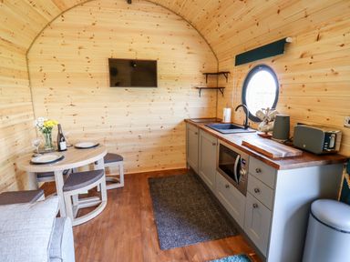 A small kitchen and dining area with wooden walls and ceiling at The Happy Valley Pod in Chipping Norton