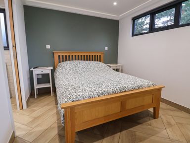 A bedroom with a wooden bed and two white nightstands at The Nest in Prestatyn