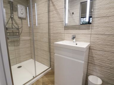 A bathroom with a shower enclosure sink unit and mirror at The Nest in Prestatyn