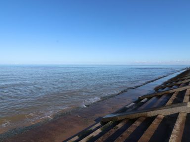 A coastal scene with concrete steps leading to the sea at The Nest in Prestatyn