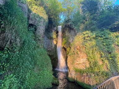 A waterfall flowing between rocky cliffs with green vegetation and trees around at The Nest in Prestatyn