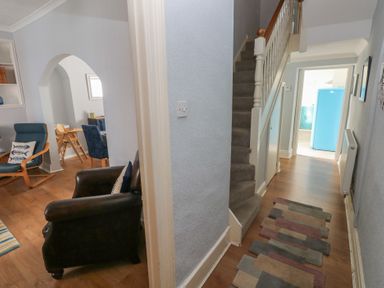 A hallway with a staircase and armchairs at Longmoor in Tenby