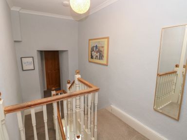 A hallway with a staircase and a painting at Longmoor in Tenby