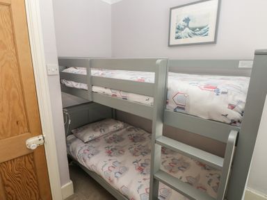 A bedroom with a bunk bed and artwork at Longmoor in Tenby