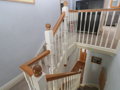 A staircase with a handrail in a hallway at Longmoor in Tenby