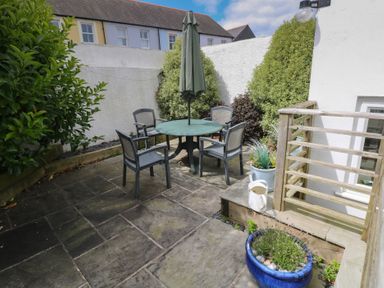 A garden with a table and chairs at Longmoor in Tenby