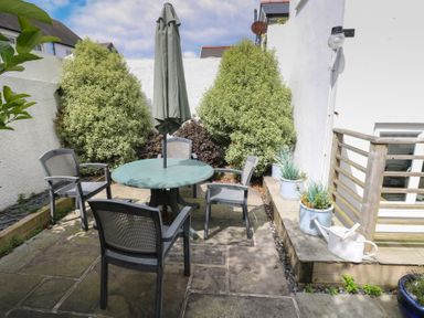 A garden area with a table and chairs at Longmoor in Tenby