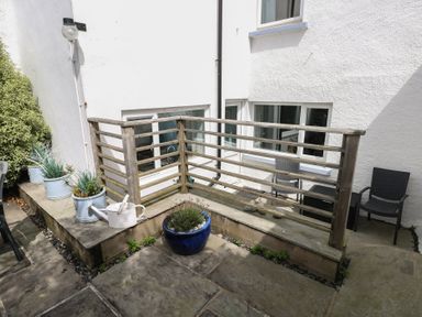 An outdoor area with a wooden balcony and planters at Longmoor in Tenby