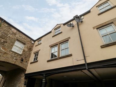Exterior view of a building with multiple windows and satellite dishes attached to the wall at Lavenna in Alnwick