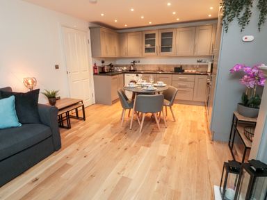 A kitchen and dining area with a round table and chairs gray cabinets and wooden floor at Lavenna in Alnwick