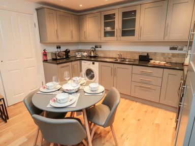 A kitchen with a dining table set for four and grey cabinets at Lavenna in Alnwick