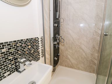 A bathroom shower area with a sink and modern faucet at Gull Cottage in Hermon near Newborough