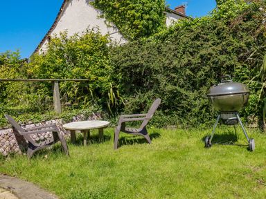 A garden with two chairs a small round table and a barbecue grill at Abalone in Bude