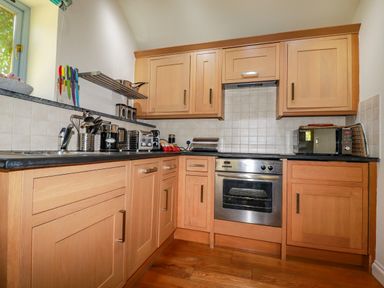 A kitchen with wooden cabinets appliances and utensils at Abalone in Bude