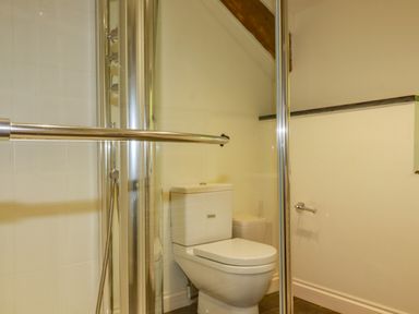 A bathroom with a toilet and a glass shower enclosure at Abalone in Bude