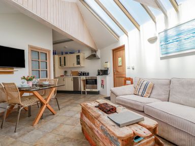 An open plan living area with a kitchen sofa wooden coffee table and dining table at Seashells Atlantic Highway near Bude