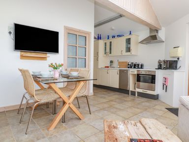 A kitchen and dining area with a glass table and wicker chairs at Seashells Atlantic Highway near Bude