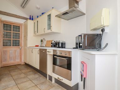 A kitchen with cream cabinets stainless steel oven and dishwasher microwave and wooden door at Seashells Atlantic Highway near Bude