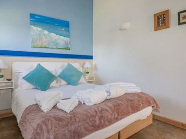A bedroom with a bed with blue pillows white towels and a painting on the wall at Seashells Atlantic Highway near Bude