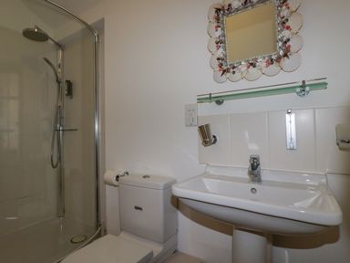 A bathroom with a shower enclosure toilet sink and a seashell framed mirror at Seashells in Atlantic Highway near Bude