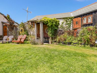 A garden with lawn chairs and a small shelter covered with plants at Seashells Atlantic Highway near Bude