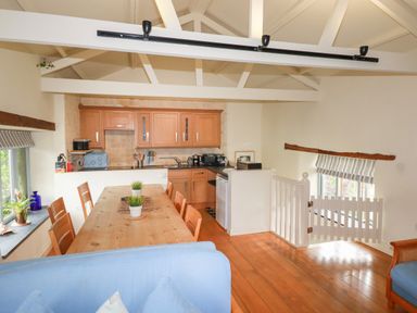 A kitchen and dining area with wooden dining table and chairs near windows at Oyster Atlantic Highway near Bude