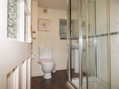 A bathroom with a toilet a framed starfish picture a shower enclosure and a sink at Oyster Atlantic Highway near Bude