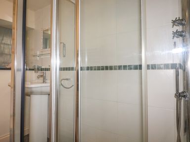 A bathroom with a glass shower enclosure a white sink a mirror and a towel ring at Oyster Atlantic Highway near Bude