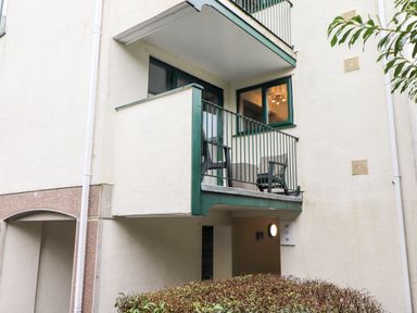 A balcony with two chairs and a small table outside a building with a light on and numbered signs at Bluebell Hill in Bowness-On-Windermere