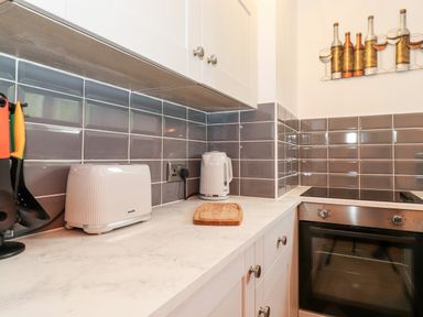 A kitchen countertop with a toaster kettle cutting board and stove at Bluebell Hill in Bowness-On-Windermere