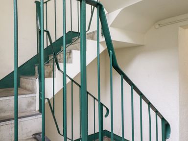 A stairwell with green metal railings and concrete steps at Bluebell Hill in Bowness-On-Windermere