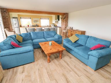 A living room with blue sofas a wooden coffee table and an open kitchen at Landfall in St Twynnells near Pembroke