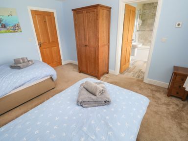 A bedroom with two single beds and a wooden wardrobe at Landfall in St Twynnells near Pembroke