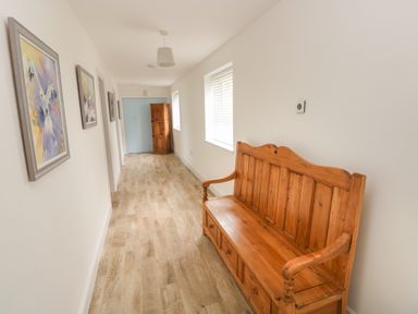 A hallway with wooden bench and paintings on the wall at Landfall in St Twynnells near Pembroke