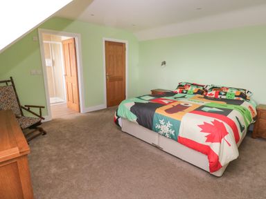 A bedroom with a bed a wooden chair two doors and a green wall at Landfall in St Twynnells near Pembroke