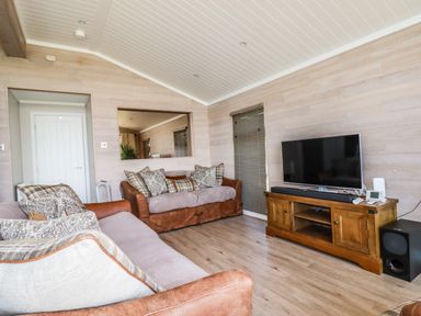 A living room with two sofas a wooden TV cabinet a flat-screen TV and a speaker at Atlantic Lodge Atlantic Highway near Bude
