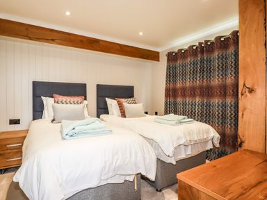 A bedroom with two single beds side by side with pillows and folded towels on top at Atlantic Lodge Atlantic Highway near Bude