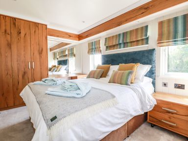A bedroom with a bed towels pillows bedside table and wooden wardrobe at Atlantic Lodge Atlantic Highway near Bude