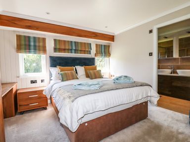 A bedroom with a bed with pillows and folded towels with an adjacent bathroom at Atlantic Lodge Atlantic Highway near Bude