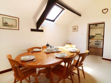 A dining room with a wooden table and six chairs set for breakfast at The Corn Tallet in Westleigh near Bideford