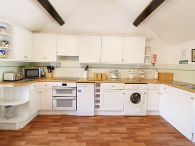A kitchen with white cabinets wooden countertops and appliances including oven dishwasher and washing machine at The Corn Tallet Westleigh near Bideford
